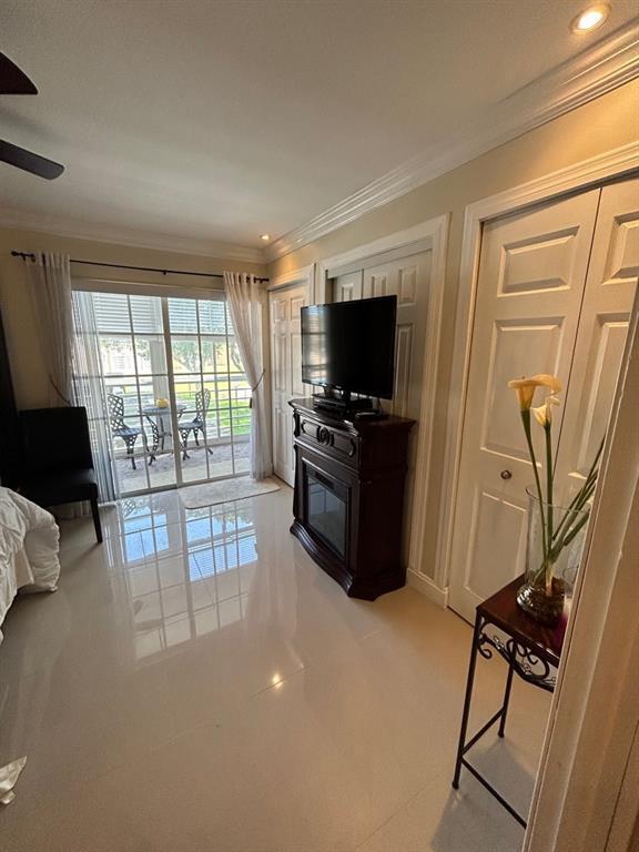 living room with light tile patterned floors, ceiling fan, and ornamental molding