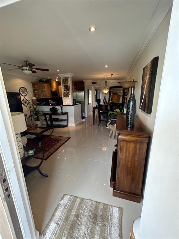 corridor with crown molding and light tile patterned floors