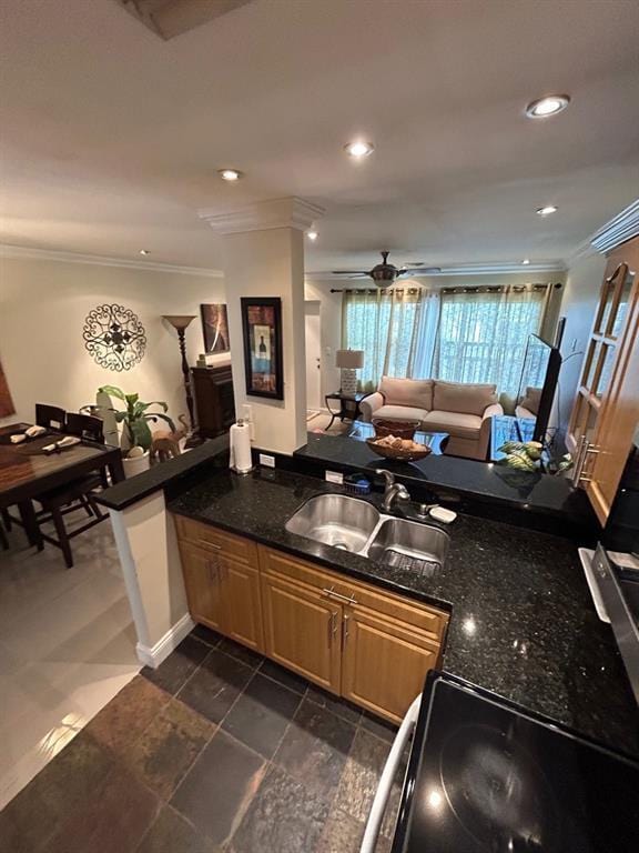 kitchen with kitchen peninsula, ornamental molding, dark stone countertops, and sink