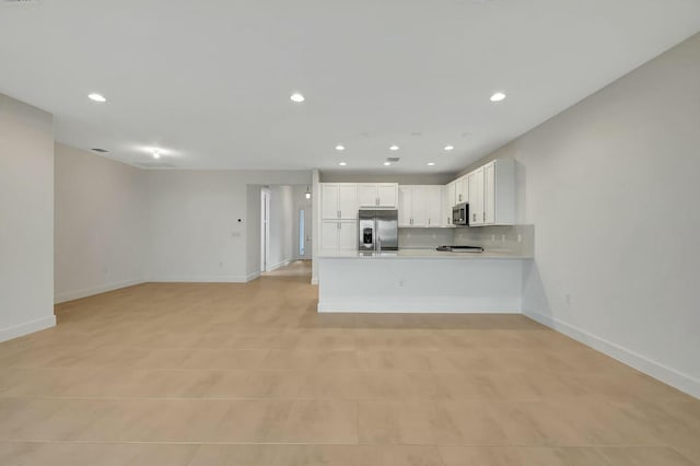 kitchen featuring tasteful backsplash, kitchen peninsula, white cabinets, and stainless steel appliances