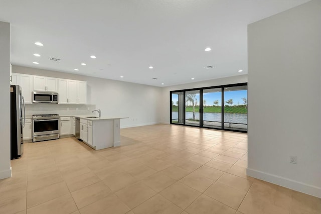 kitchen featuring white cabinetry, stainless steel appliances, light tile patterned floors, kitchen peninsula, and a water view