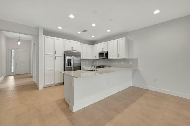 kitchen featuring kitchen peninsula, stainless steel appliances, sink, light tile patterned floors, and white cabinetry