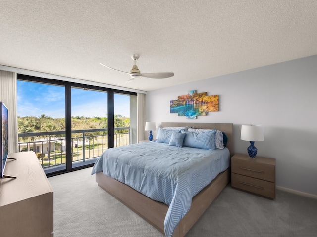 bedroom with a textured ceiling, access to outside, a wall of windows, and carpet floors