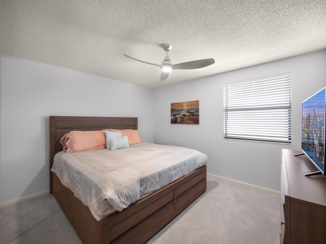 bedroom with a textured ceiling, baseboards, a ceiling fan, and light colored carpet