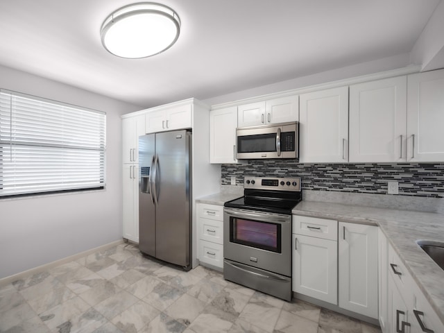 kitchen featuring tasteful backsplash, white cabinets, light stone counters, marble finish floor, and stainless steel appliances