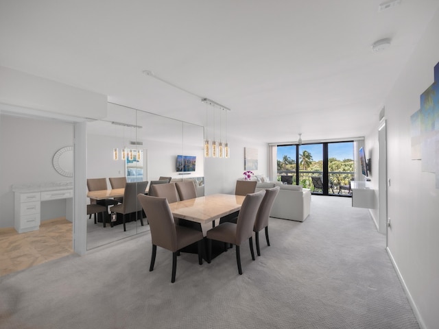 dining space with floor to ceiling windows, light carpet, and baseboards