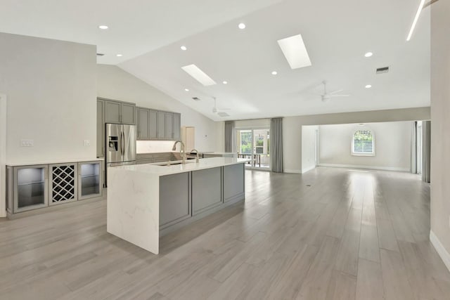 kitchen featuring gray cabinetry, ceiling fan, stainless steel fridge, a spacious island, and light hardwood / wood-style floors