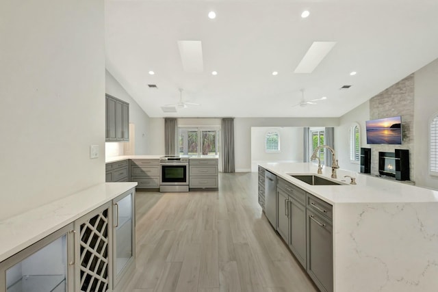 kitchen featuring gray cabinetry, a healthy amount of sunlight, lofted ceiling with skylight, and appliances with stainless steel finishes