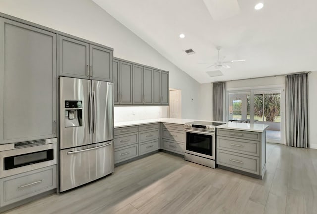 kitchen featuring kitchen peninsula, gray cabinets, vaulted ceiling, and appliances with stainless steel finishes