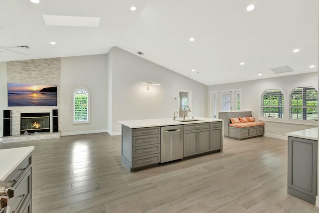 kitchen with gray cabinetry, sink, stainless steel dishwasher, and light hardwood / wood-style flooring