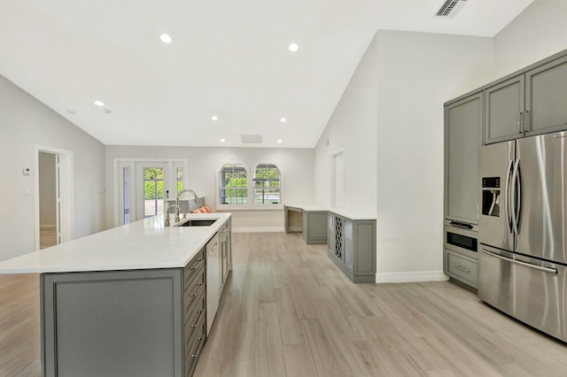 kitchen with stainless steel fridge with ice dispenser, gray cabinets, lofted ceiling, and sink