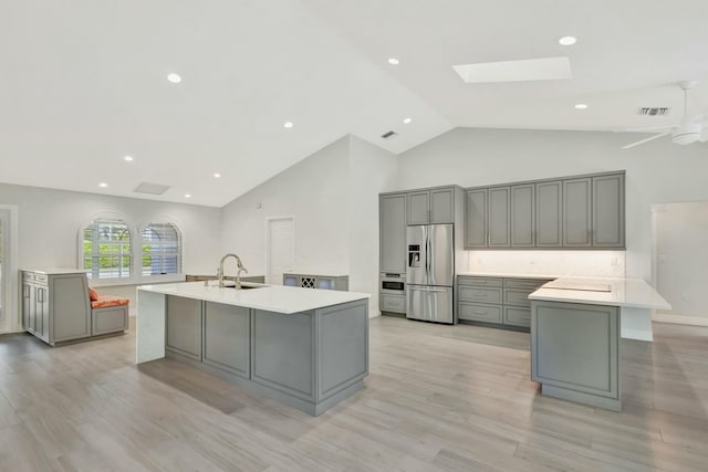 kitchen featuring appliances with stainless steel finishes, light wood-type flooring, a skylight, gray cabinetry, and a large island