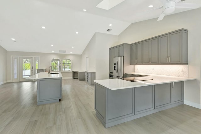 kitchen featuring kitchen peninsula, gray cabinets, stainless steel refrigerator with ice dispenser, and light wood-type flooring