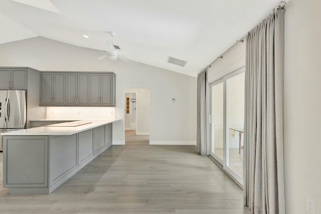 kitchen featuring kitchen peninsula, stainless steel fridge, light hardwood / wood-style flooring, and lofted ceiling