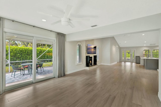 unfurnished living room featuring a fireplace, hardwood / wood-style floors, vaulted ceiling, and ceiling fan