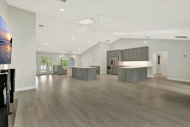 unfurnished living room with ceiling fan, light hardwood / wood-style floors, and lofted ceiling