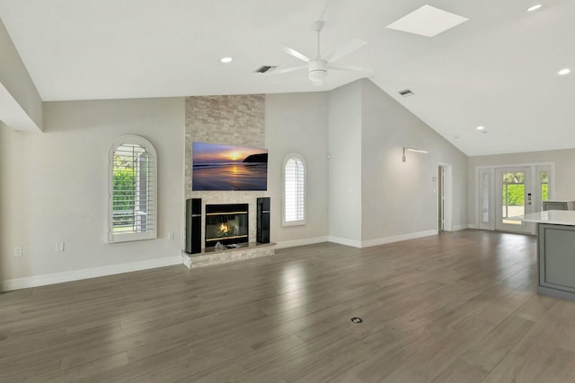 unfurnished living room with high vaulted ceiling, hardwood / wood-style flooring, a stone fireplace, and ceiling fan