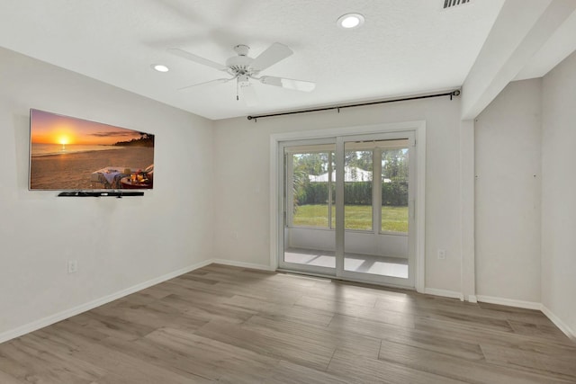 spare room with ceiling fan, light hardwood / wood-style flooring, and a textured ceiling