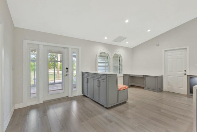 kitchen with gray cabinets, kitchen peninsula, light hardwood / wood-style floors, and vaulted ceiling