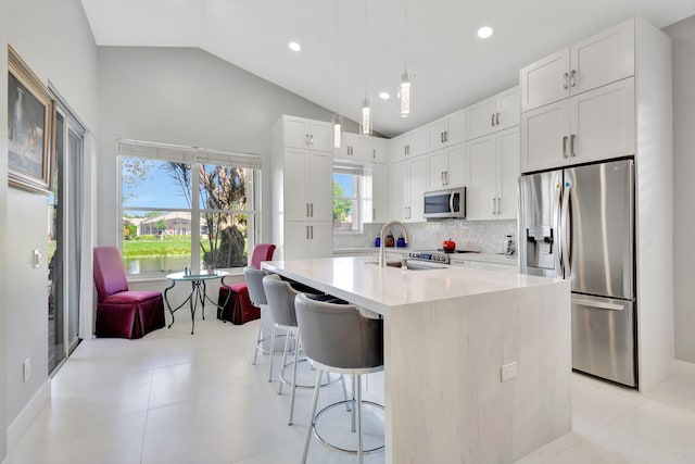 kitchen featuring a kitchen breakfast bar, white cabinets, pendant lighting, and appliances with stainless steel finishes