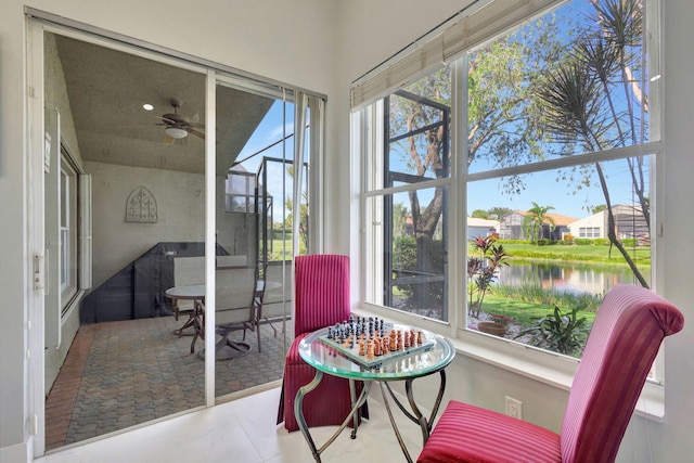 sunroom featuring a water view and ceiling fan