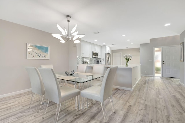 dining space featuring light hardwood / wood-style flooring and a notable chandelier