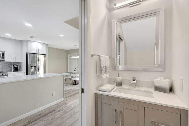 bathroom with backsplash, hardwood / wood-style floors, and vanity