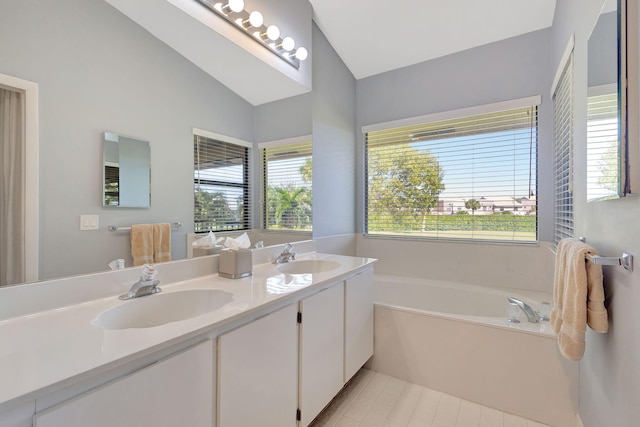 bathroom with tile patterned floors, a bathing tub, vanity, and vaulted ceiling