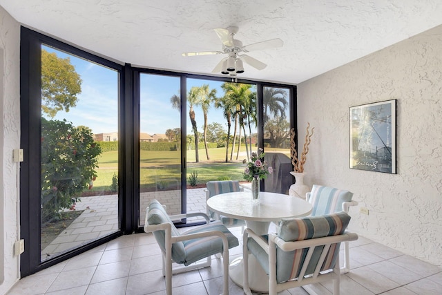 dining room featuring ceiling fan, expansive windows, light tile patterned floors, and a textured ceiling