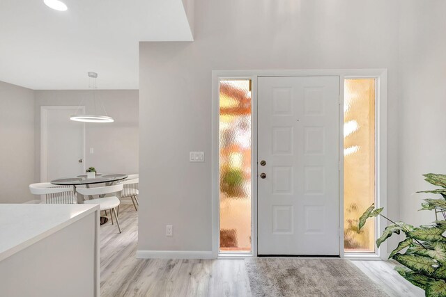 kitchen featuring white cabinets, hanging light fixtures, appliances with stainless steel finishes, light hardwood / wood-style floors, and kitchen peninsula