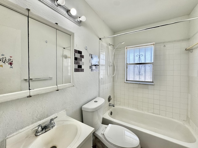 full bathroom with toilet, shower / tub combination, vanity, and a textured wall