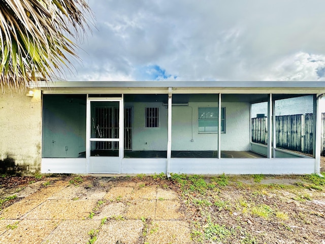 back of property featuring a sunroom and stucco siding