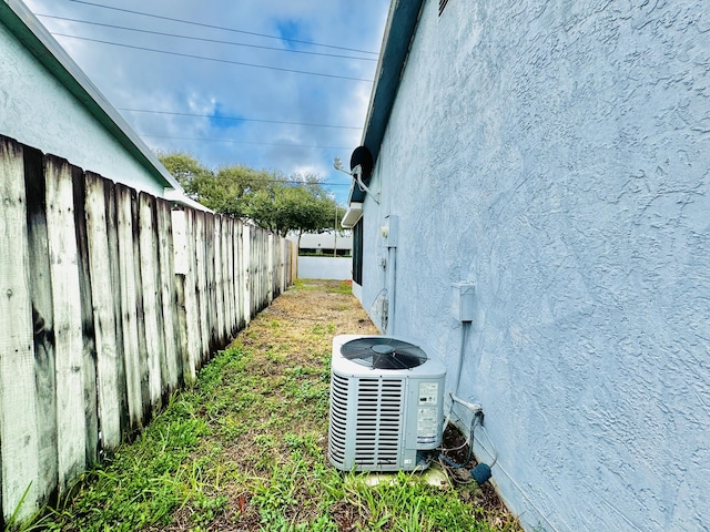 exterior details featuring central air condition unit, fence, and stucco siding