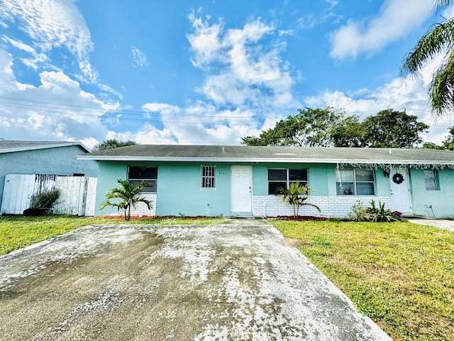 single story home with driveway, brick siding, fence, and a front yard