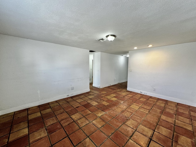 empty room featuring a textured ceiling, recessed lighting, visible vents, and baseboards