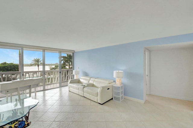 living area with light tile patterned floors, a wall of windows, a water view, and baseboards