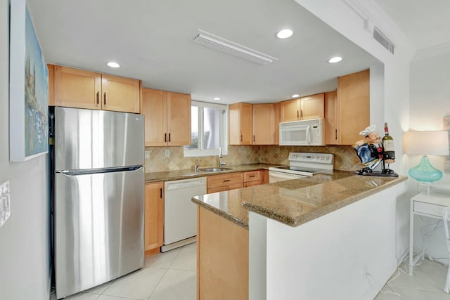 kitchen with white appliances, decorative backsplash, sink, kitchen peninsula, and light stone counters