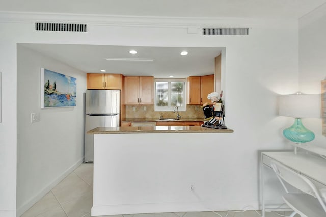 kitchen with tasteful backsplash, sink, stainless steel fridge, ornamental molding, and light tile patterned floors