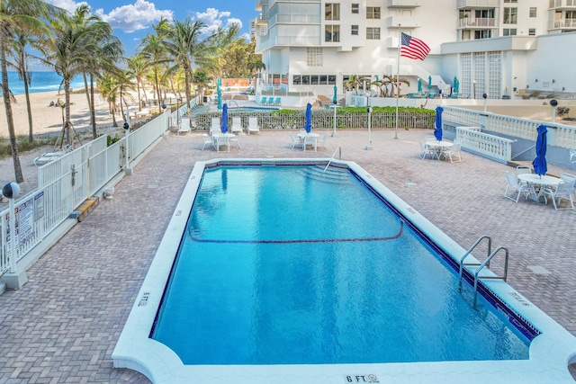 view of pool featuring a water view and a patio area