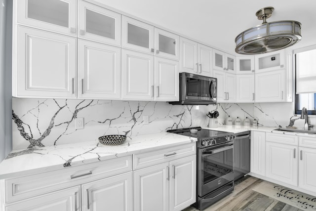 kitchen featuring sink, decorative backsplash, light stone countertops, appliances with stainless steel finishes, and white cabinetry