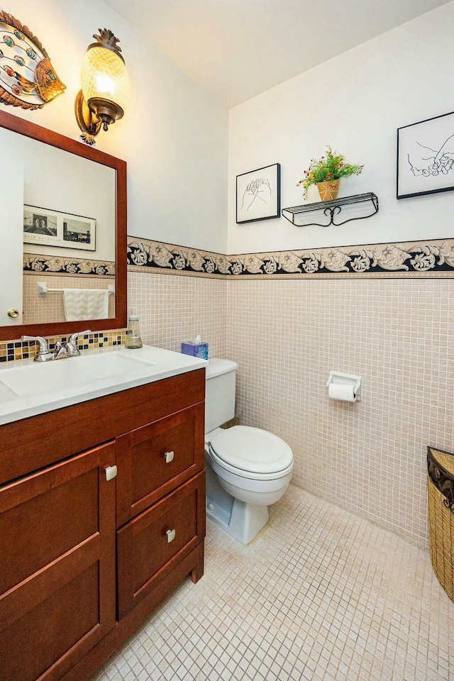 bathroom with tile patterned floors, vanity, tile walls, and toilet