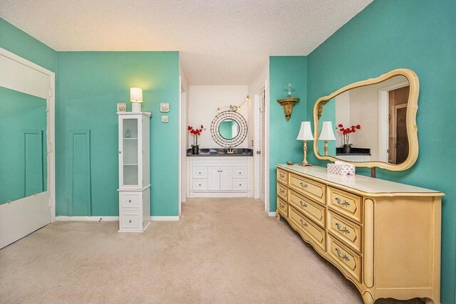 bedroom with a textured ceiling, light carpet, and connected bathroom