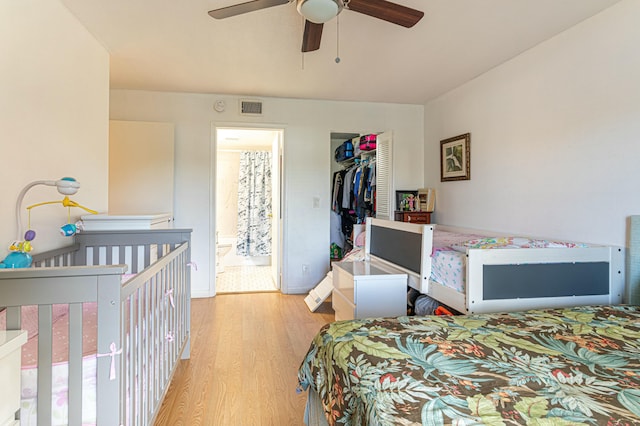 bedroom featuring a closet, visible vents, light wood-style flooring, a ceiling fan, and connected bathroom