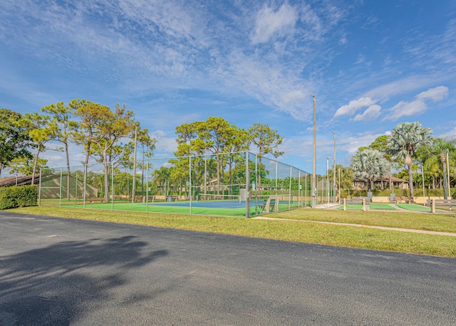 view of home's community featuring a tennis court and fence