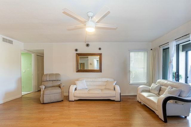 living room featuring ceiling fan, light wood finished floors, visible vents, and baseboards