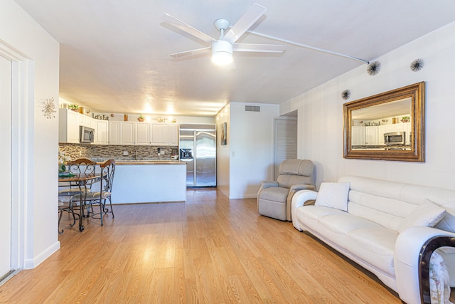 living area featuring visible vents, ceiling fan, light wood-style flooring, and baseboards