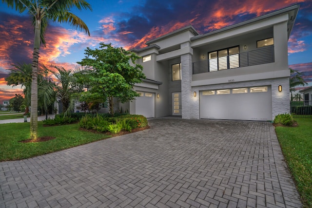 view of front of home with a yard, a garage, and a balcony