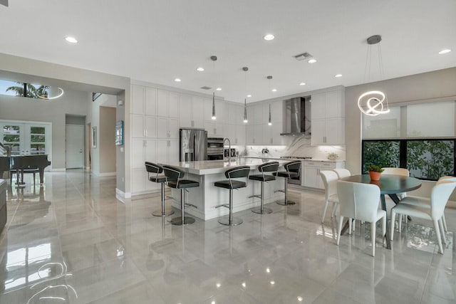 kitchen with white cabinetry, pendant lighting, appliances with stainless steel finishes, and wall chimney exhaust hood