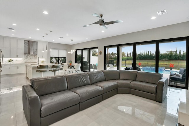 tiled living room featuring ceiling fan and sink