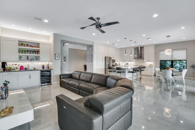 tiled living room with ceiling fan, sink, and wine cooler